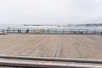 the wooden floor of a pier with a yellow surf board in the water behind it