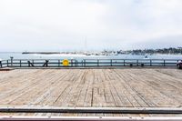 the wooden floor of a pier with a yellow surf board in the water behind it