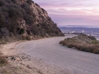 a lone motorcycle is riding up an empty road at dusk in the mountains area above san gabriel