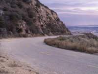 a lone motorcycle is riding up an empty road at dusk in the mountains area above san gabriel