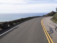 the curved road stretches towards the ocean to make it appear it is a straight curve