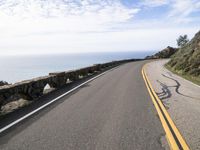 the curved road stretches towards the ocean to make it appear it is a straight curve