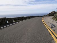 the curved road stretches towards the ocean to make it appear it is a straight curve