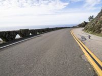 the curved road stretches towards the ocean to make it appear it is a straight curve