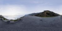 the sky is blue and cloudy above the ocean in this 360 - angle view of a road