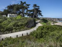 a long road next to a beach in front of some trees and bushes next to a cliff