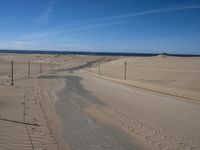 a paved beach with a fence in front of it and the ocean in the distance