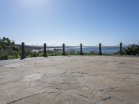 a stone floor with poles and a view of the ocean in the distance with mountains