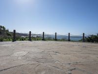 a stone floor with poles and a view of the ocean in the distance with mountains