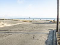 a traffic signal on a city street next to the ocean's edge while the sun is shining