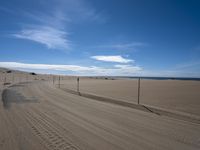 a paved beach with a fence in front of it and the ocean in the distance