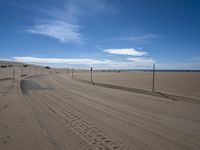 a paved beach with a fence in front of it and the ocean in the distance