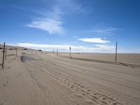 a paved beach with a fence in front of it and the ocean in the distance