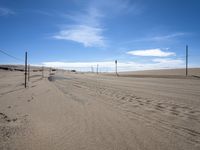 a paved beach with a fence in front of it and the ocean in the distance