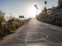 a bike with the sun in the background at the end of the road from the side of a cliff