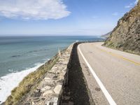 the road along the ocean is empty in most parts of california, and there's a lone person on one side