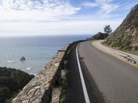 the road along the ocean is empty in most parts of california, and there's a lone person on one side