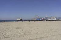 people walk on sand at a beach, near the ocean in the distance is a sky with few cloudless, and blue skies