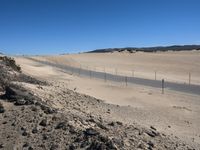 a paved beach with a fence in front of it and the ocean in the distance