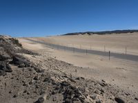 a paved beach with a fence in front of it and the ocean in the distance