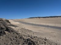 a paved beach with a fence in front of it and the ocean in the distance