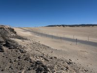 a paved beach with a fence in front of it and the ocean in the distance