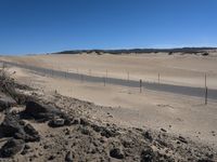 a paved beach with a fence in front of it and the ocean in the distance