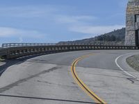 a bridge crossing over an empty road near a hill in the countryside with blue skies