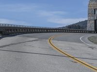 a bridge crossing over an empty road near a hill in the countryside with blue skies