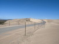 a paved beach with a fence in front of it and the ocean in the distance