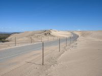 a paved beach with a fence in front of it and the ocean in the distance