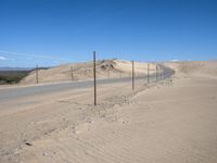 a paved beach with a fence in front of it and the ocean in the distance