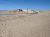 a paved beach with a fence in front of it and the ocean in the distance