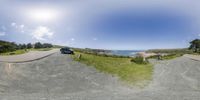 a van is parked on the side of a road by the ocean and the grass is all over