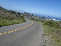 an empty road on a hill overlooking the ocean and a rocky coastline in the distance