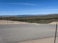 a paved beach with a fence in front of it and the ocean in the distance