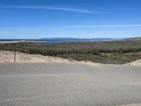 a paved beach with a fence in front of it and the ocean in the distance