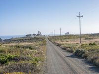 the road to the beach near a couple of power lines is empty and dirty,