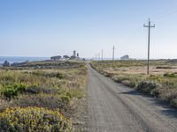 the road to the beach near a couple of power lines is empty and dirty,