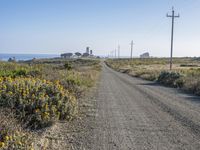 the road to the beach near a couple of power lines is empty and dirty,