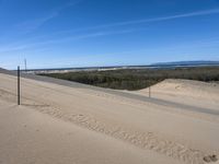 a paved beach with a fence in front of it and the ocean in the distance