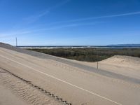 a paved beach with a fence in front of it and the ocean in the distance