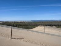 a paved beach with a fence in front of it and the ocean in the distance