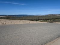 a paved beach with a fence in front of it and the ocean in the distance