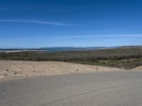 a paved beach with a fence in front of it and the ocean in the distance