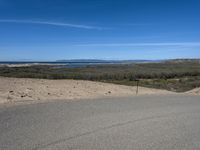 a paved beach with a fence in front of it and the ocean in the distance