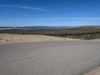 a paved beach with a fence in front of it and the ocean in the distance