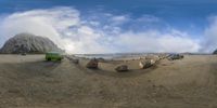 a group of cars that are on some sand in front of a rock cliff beach