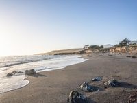 a grassy field by the shore and a cliff with rocks in the ocean in the background