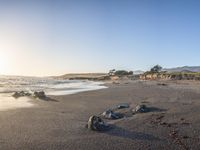 a grassy field by the shore and a cliff with rocks in the ocean in the background